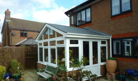 A bright conservatory featuring a white roof and large windows, showcasing a spacious and airy interior.
