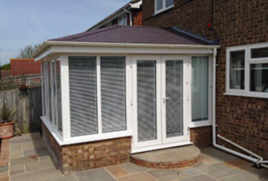 A patio featuring a white sunroom surrounded by a charming brick patio.