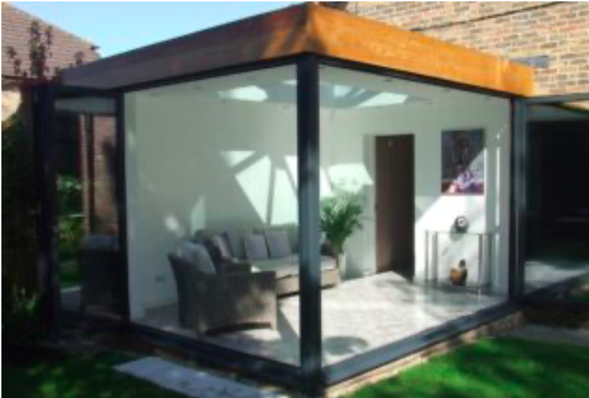 A sleek glass conservatory featuring a spacious patio area, surrounded by greenery and natural light.