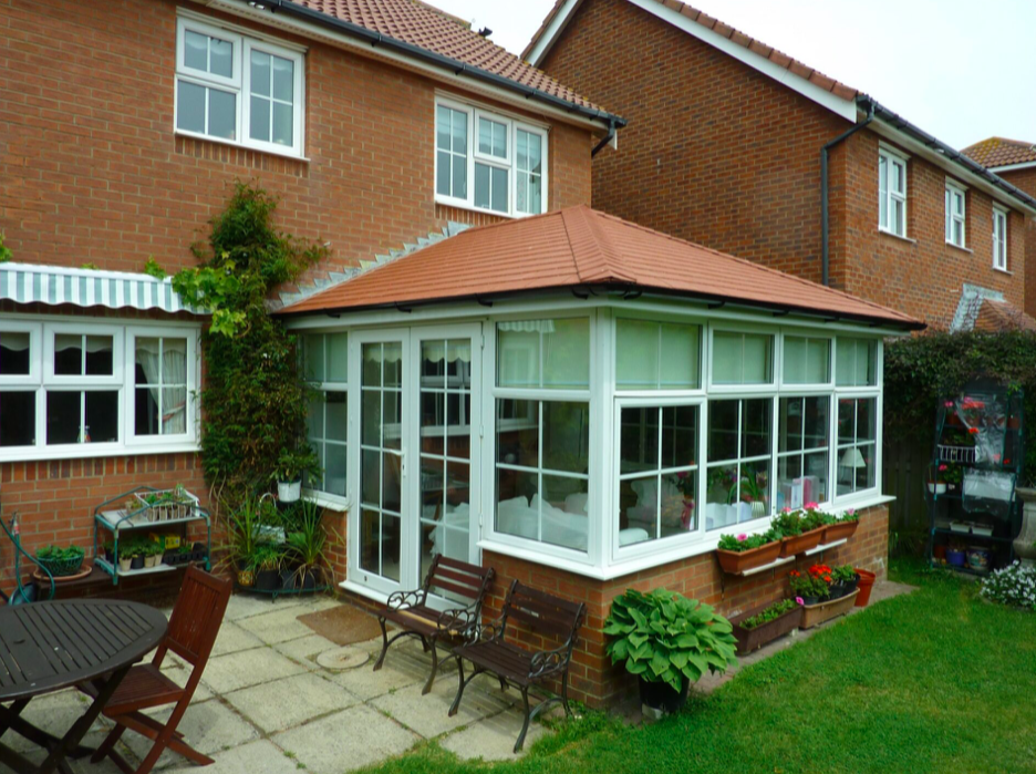 A large house featuring a spacious patio and a small garden in front.